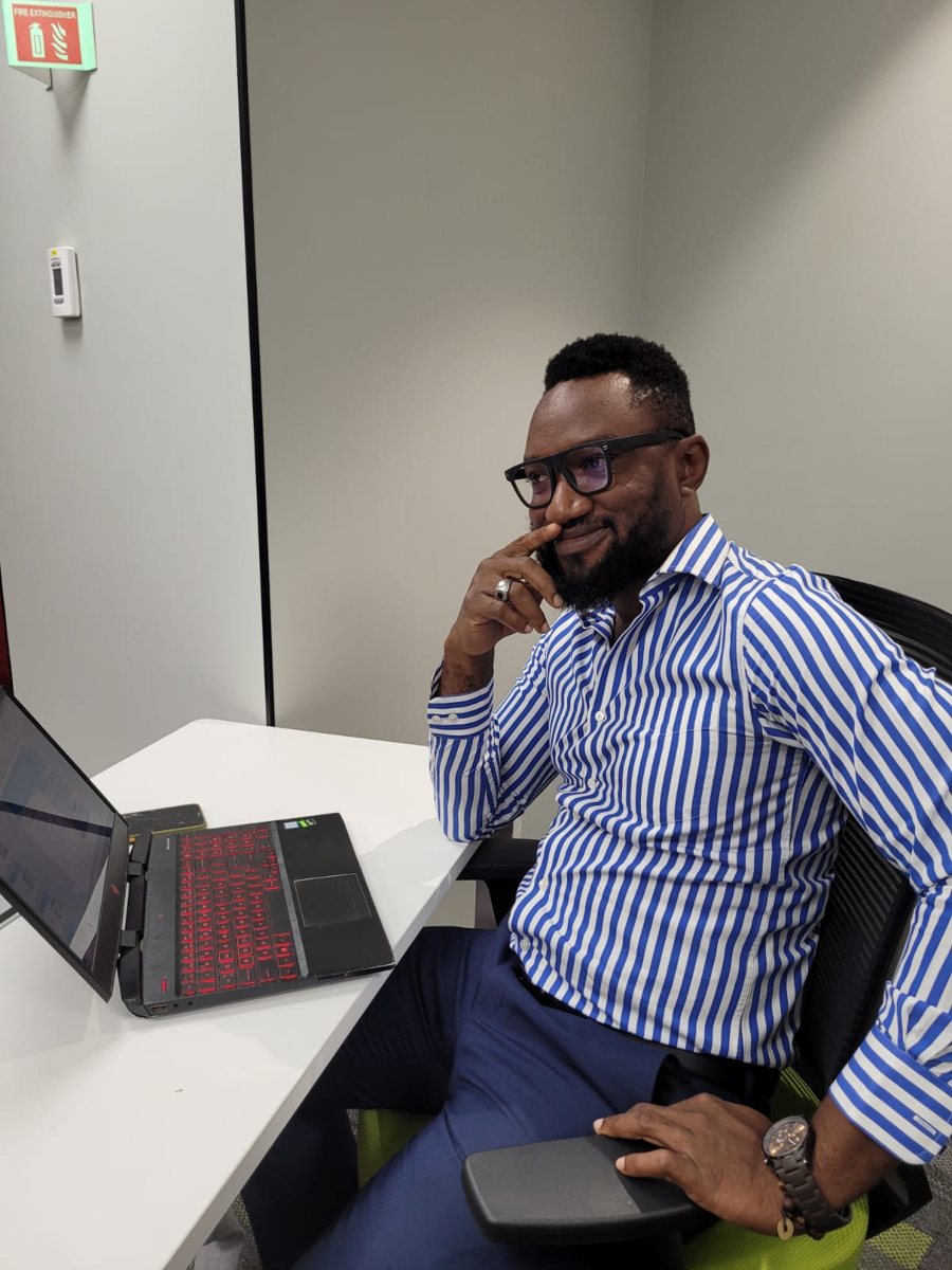 Arc. Dr. Kosi Emmanuel Chukwujindu smiling at his laptop